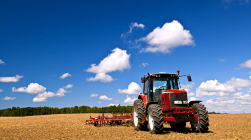 land grabbing e proprietà della terra, trattore e contadino al lavoro