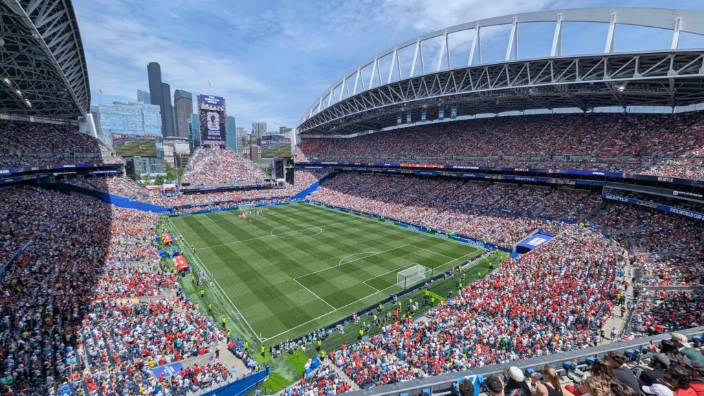 Veduta dall'alto di uno stadio gremito durante una partita della Coppa del Mondo 2026, con cartelloni pubblicitari di Aramco a bordocampo