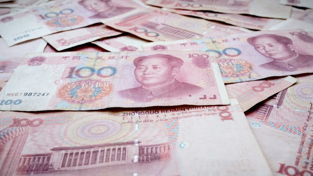 Numerose banconote da 100 yuan cinesi sparse e sovrapposte, con il ritratto di Mao Zedong