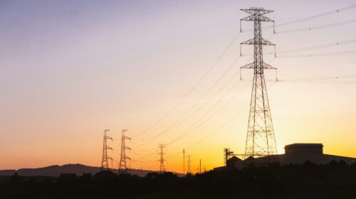 Tralicci dell'alta tensione al tramonto, simbolo della transizione energetica