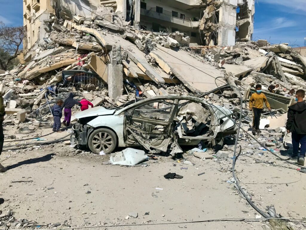 Auto distrutta davanti a un palazzo crollato dopo un bombardamento israeliano a Gaza