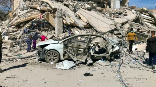 Auto distrutta davanti a un palazzo crollato dopo un bombardamento israeliano a Gaza