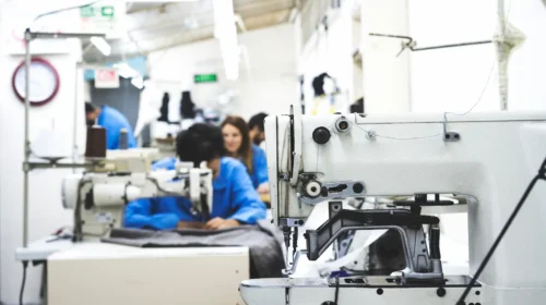 Lavoratori e lavoratrici alle macchine da cucire in un laboratorio tessile, settore al centro della campagna per il salario dignitoso