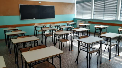 Aula scolastica italiana con banchi vuoti e vecchio radiatore, persiane abbassate