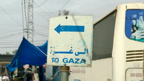 Cartello stradale con la scritta «To Gaza» in inglese e arabo accanto a un autobus