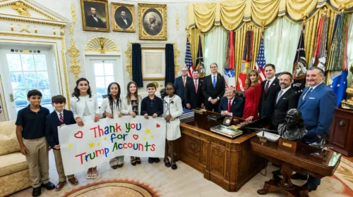 Donald Trump nello Studio Ovale con un gruppo di bambini che reggono uno striscione di ringraziamento per i Trump Accounts